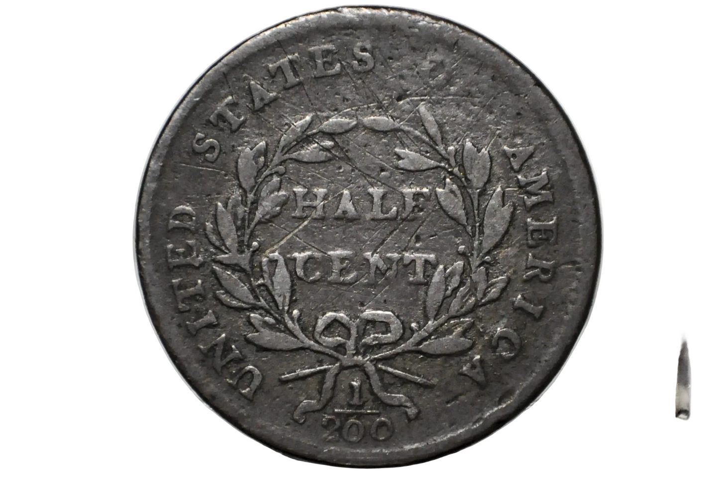 A close-up of a vintage United States Half Cent coin inside a clear plastic protective holder, showing the reverse side with a wreath and the text 'UNITED STATES HALF CENT'