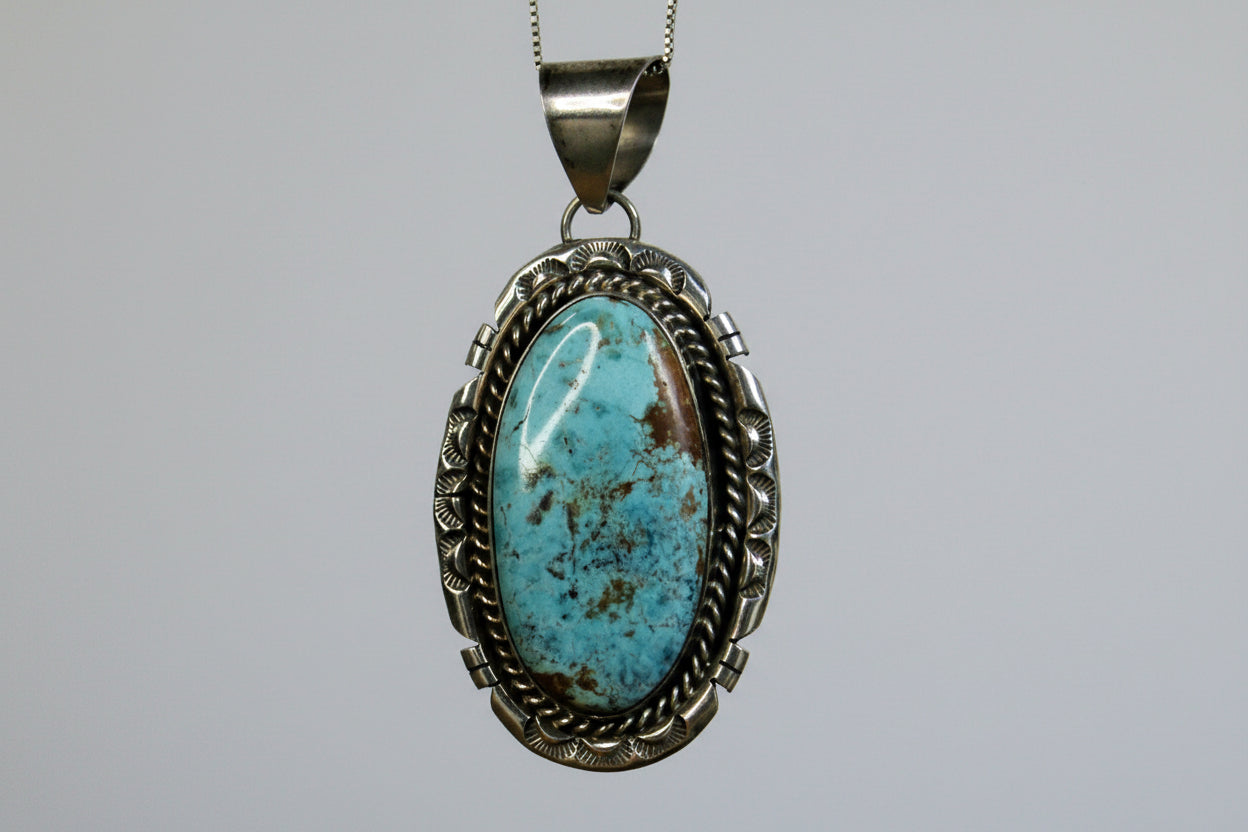 Turquoise pendant with silver frame on a gray background