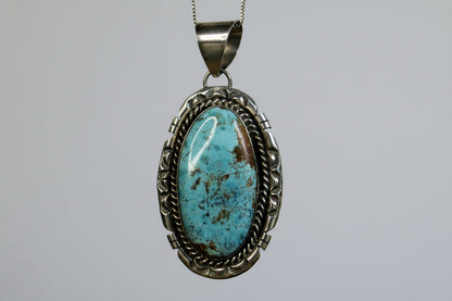Turquoise pendant with silver frame on a gray background