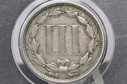 Silver coin with three vertical bars and wreath design on a dark background