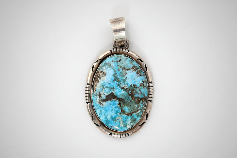 Turquoise stone pendant with silver frame on a black background