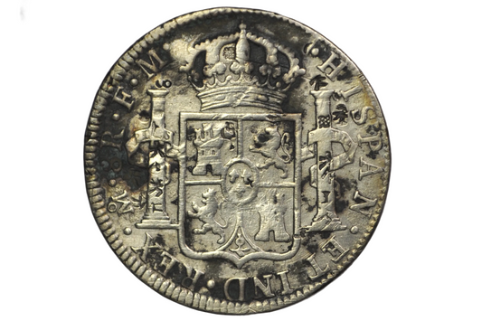 Reverse of a panish 8 reales from 1784. Two pillars on either side of a crest that is topped by a crown above. Lettering: Mo.8R.F.M. Hispan. ET IND.REX
