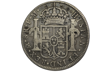 Reverse of a panish 8 reales from 1789. Two pillars on either side of a crest that is topped by a crown above. Lettering: Mo.8R.F.M. Hispan. ET IND.REX