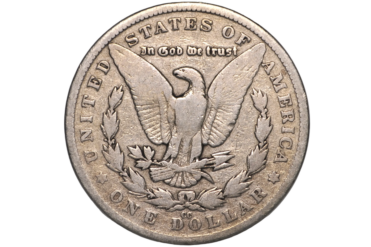 A silver US one dollar coin featuring an eagle and laurel wreath, displayed inside a clear plastic grading holder against a neutral gray background with a CC mint mark. 