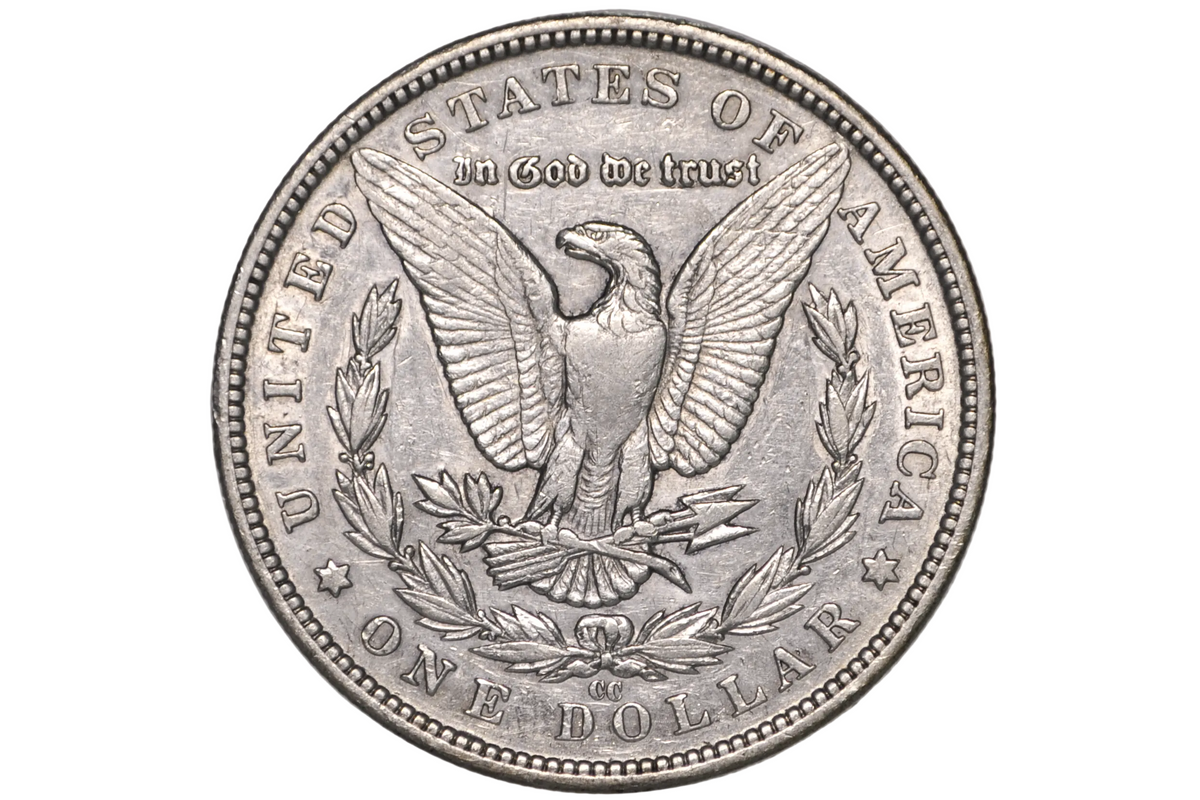 A silver US one dollar coin featuring an eagle and laurel wreath, and the cc mint mark for the Carson City mint. 
