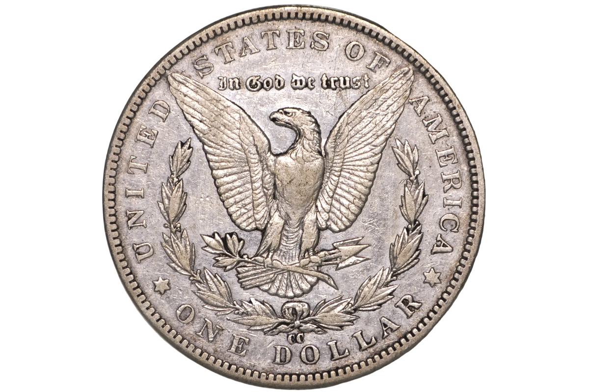A silver United States one dollar coin featuring an eagle with outstretched wings, surrounded by the text 'IN GOD WE TRUST' and 'UNITED STATES OF AMERICA' and 'ONE DOLLAR', displayed inside a clear plastic protective capsule.
