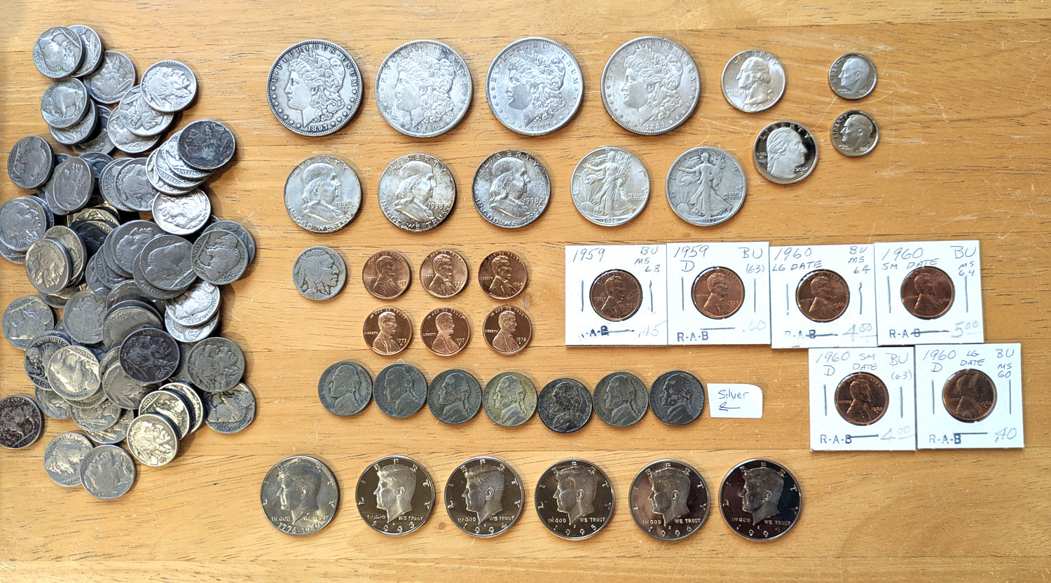 Collection of coins on a wooden surface with some displayed in holders.