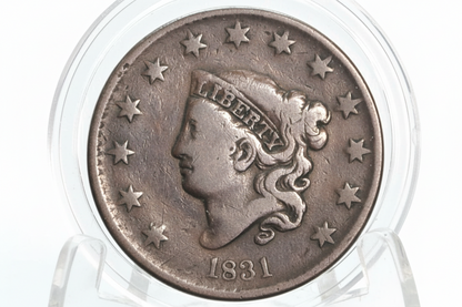 Vintage coin with 'Liberty' inscription and year '1831' on a clear holder against a dark background