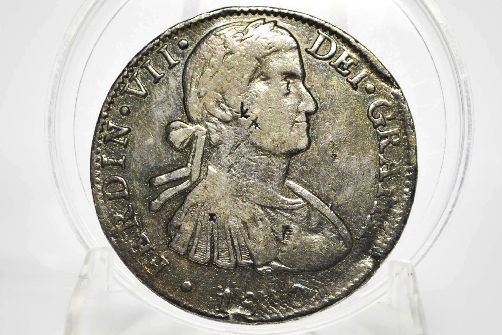 An antique silver coin featuring a profile portrait of a historical figure, displayed inside a clear protective plastic capsule on a white background.