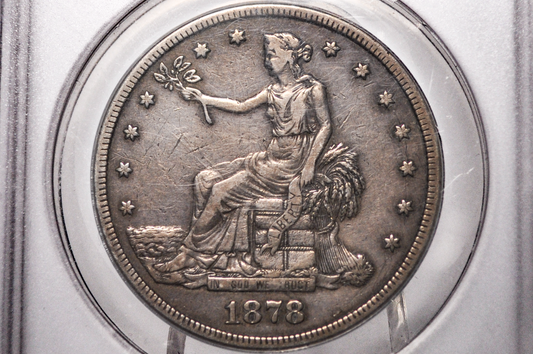 An 1878 United States silver trade dollar coin inside a clear plastic grading holder, showing the seated Liberty design with the year 1878 at the bottom.
