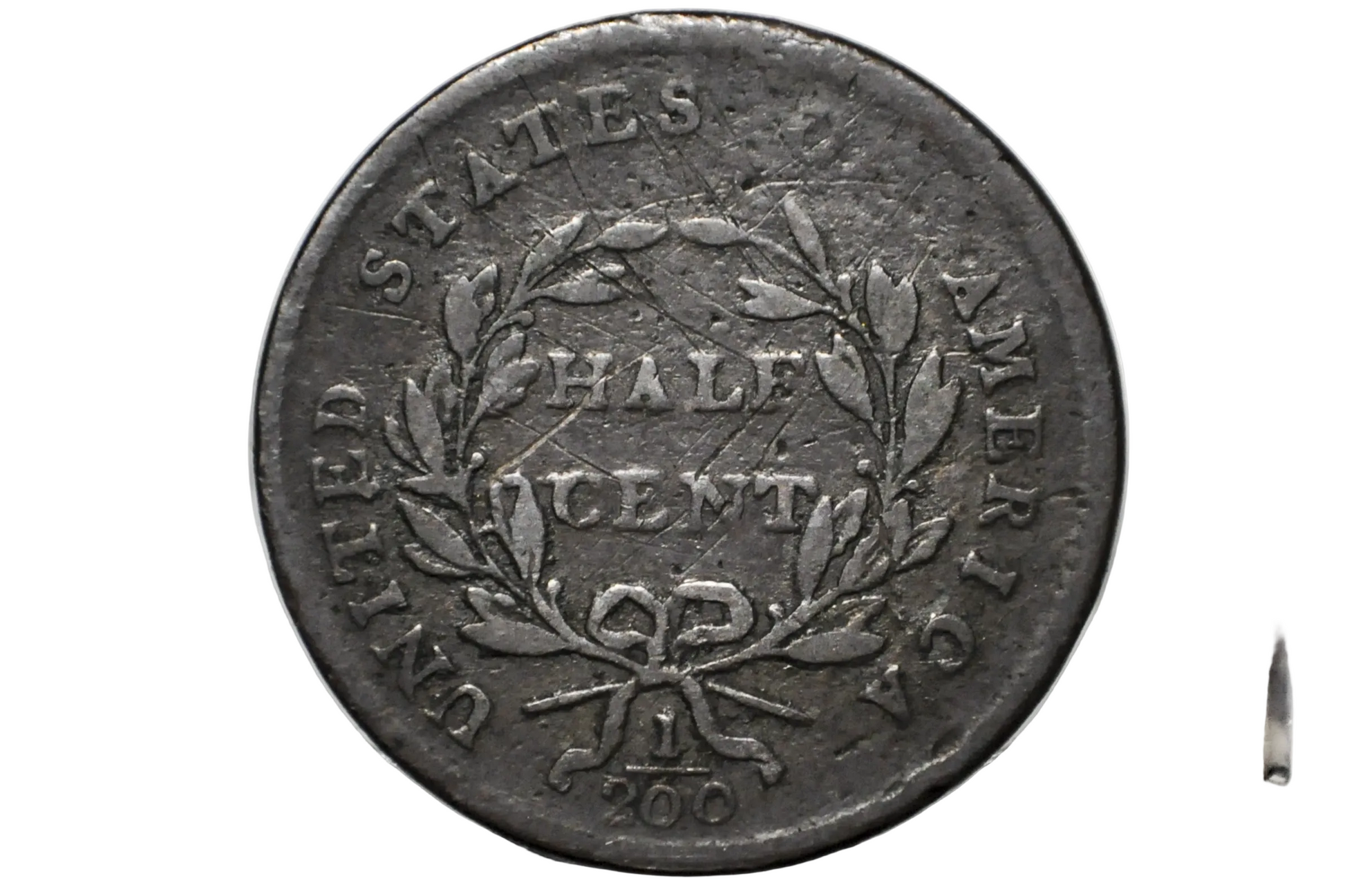 A close-up of a vintage United States Half Cent coin inside a clear plastic protective holder, showing the reverse side with a wreath and the text 'UNITED STATES HALF CENT' 